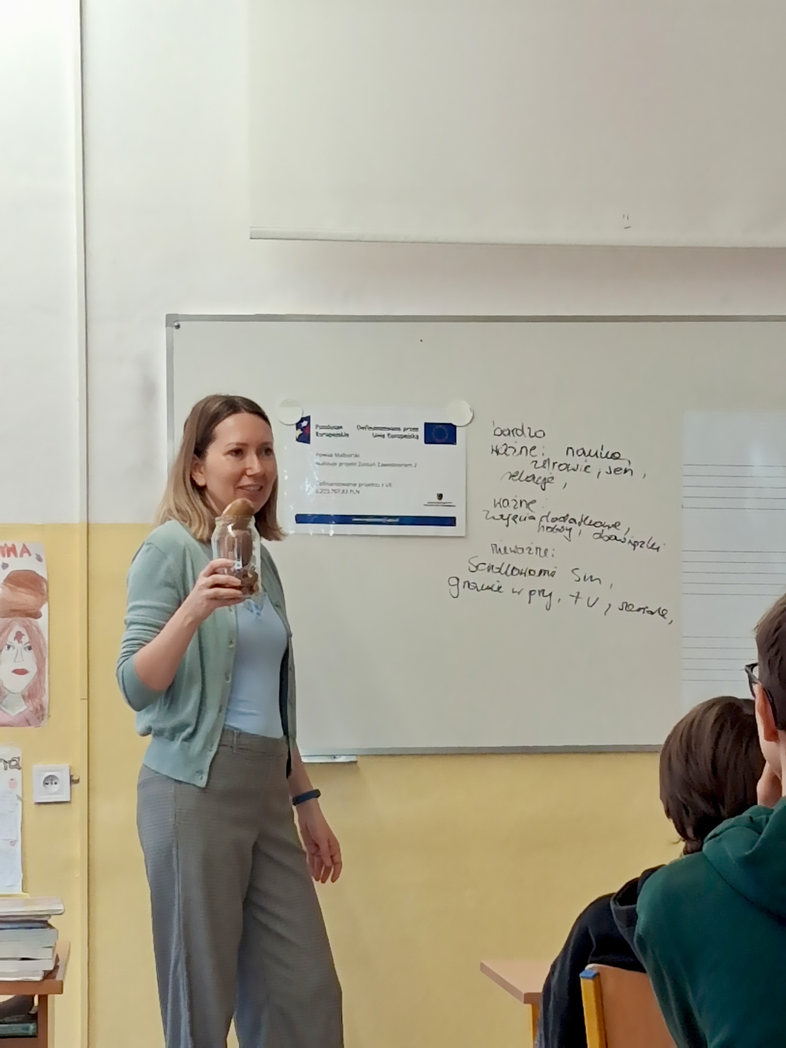Zdjęcie przedstawia Koordynatorkę, która za pomocą słoika wypełnionego różnymi przedmiotami pokazuje uczniom, jak sposób zagospodarowania czasu wpływa na przebieg naszego dnia i realizację codziennych zadań 