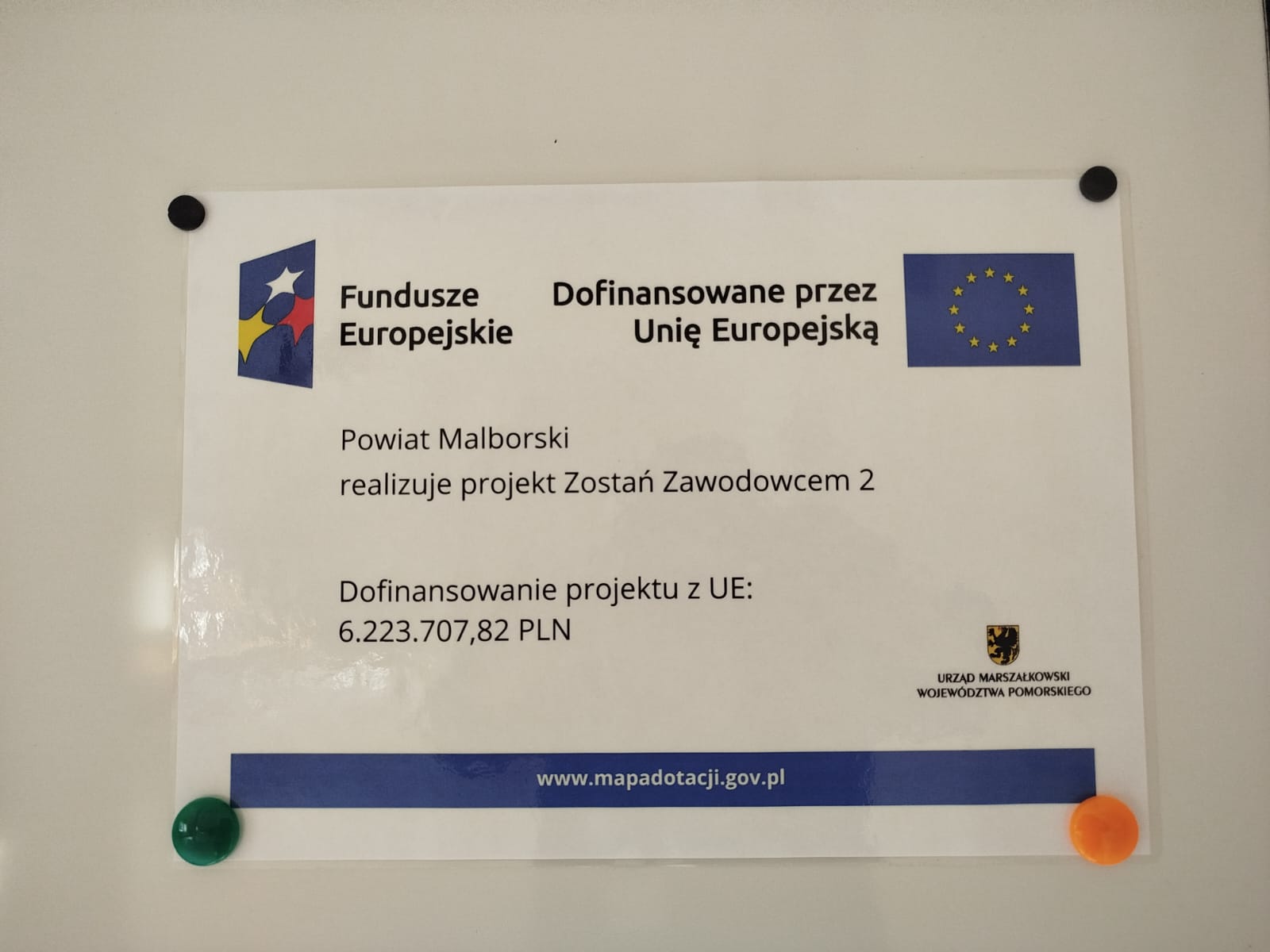 Zdjęcie przedstawia plakat wiszący na tablicy szkolnej z informacją o realizacji projektu "Zostań Zawodowcem 2" 
